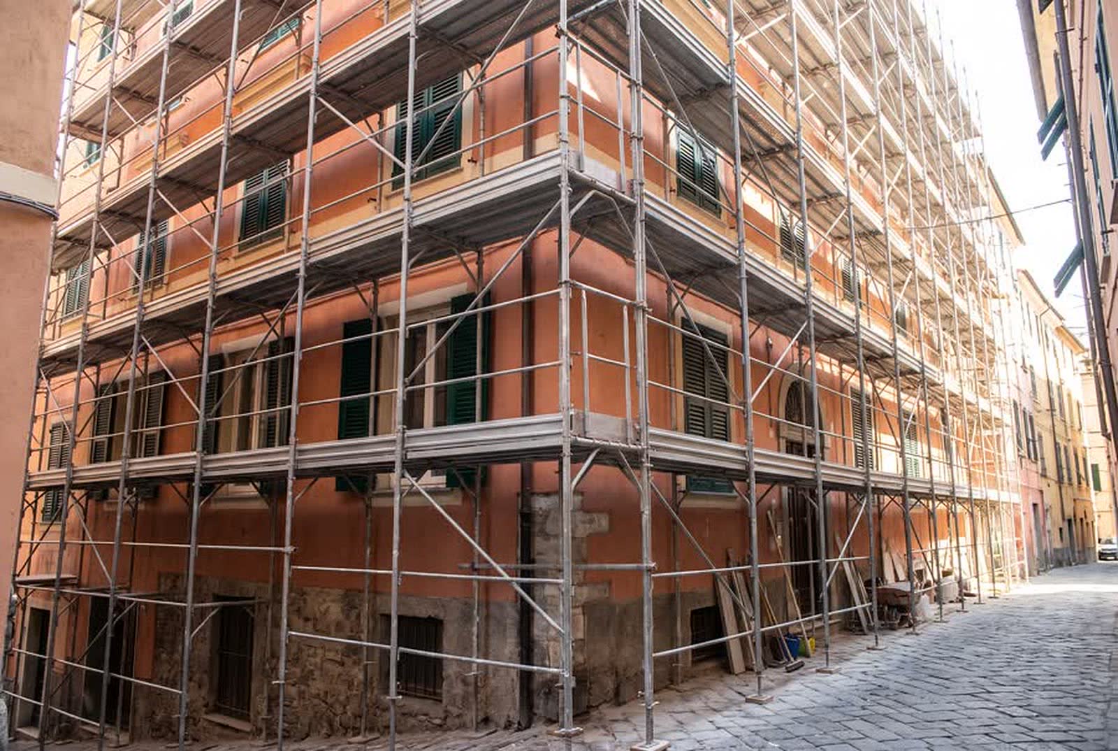 Ponteggio di facciata montato su una palazzina in intonaco color terracotta in ristrutturazione